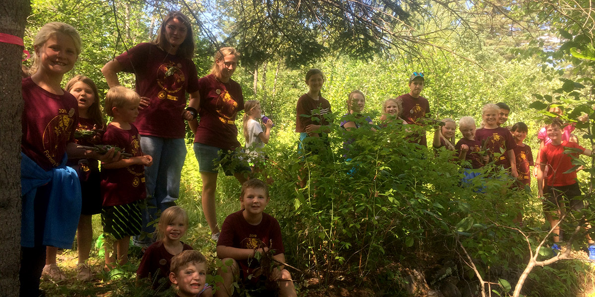 several elementary aged children and two chaperones out in the woods