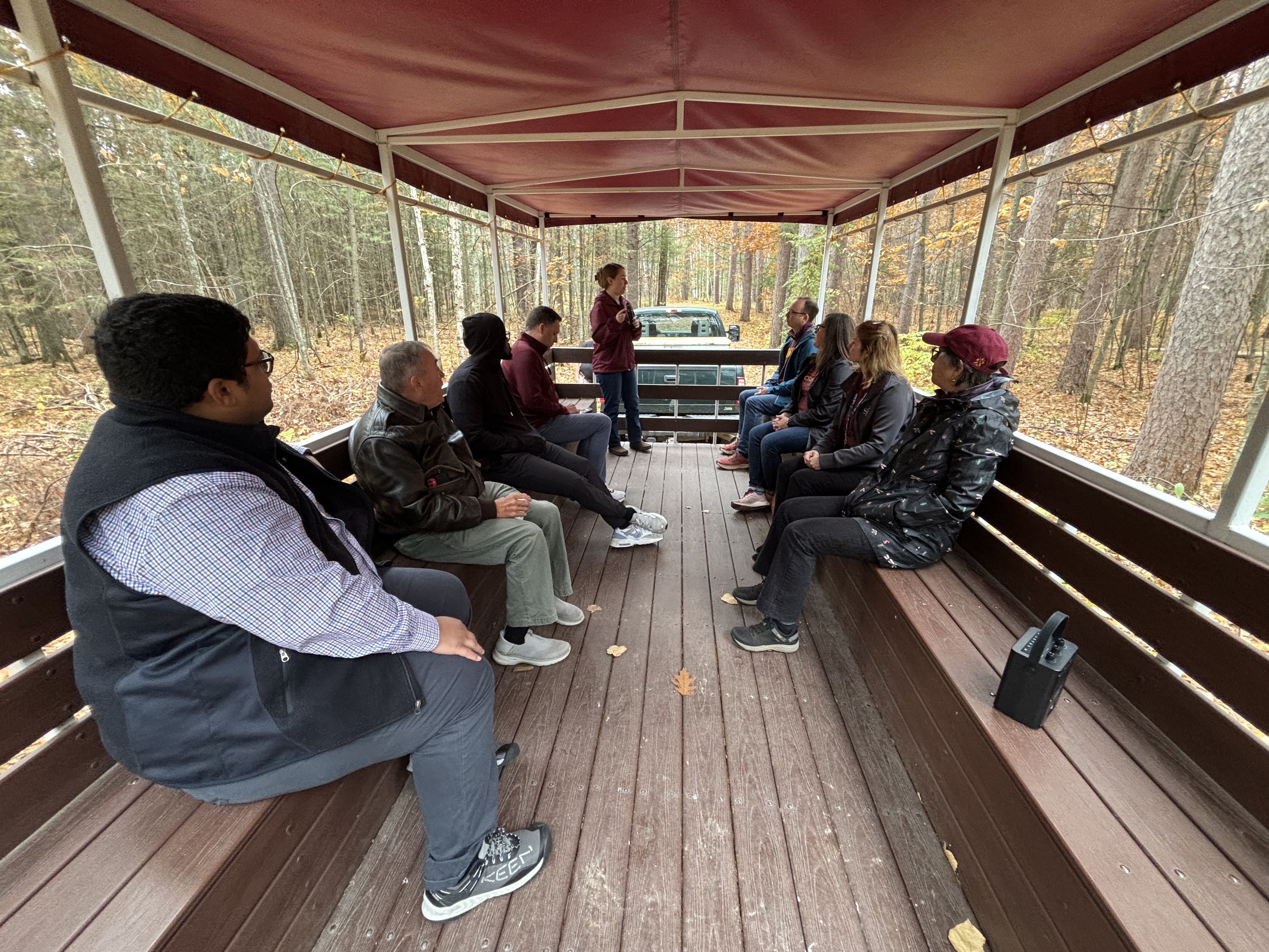 Members of the Board of Regents and others sit in a covered wagon listening to a presentation on Climate Ready Woodlands at NCROC.